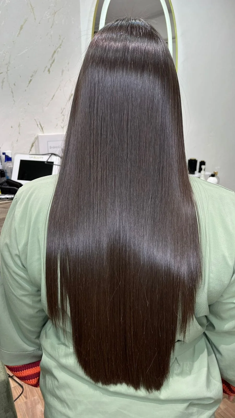 Cabello largo oscuro alisado con acabado brillante en Aura Nails Care