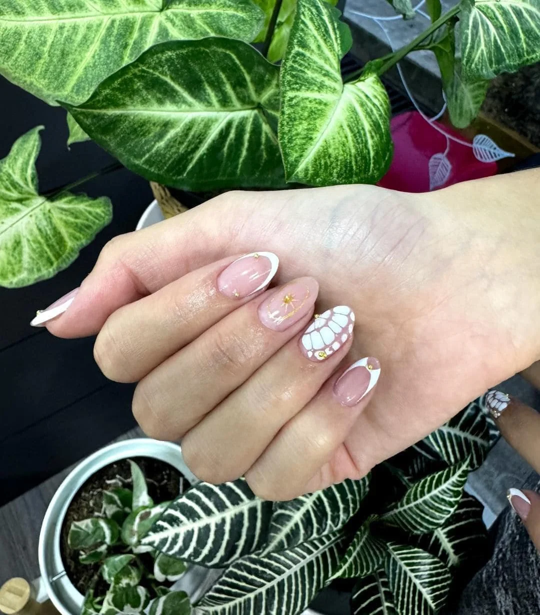 Manicure francés con diseño floral y detalles dorados en Aura Nails Care