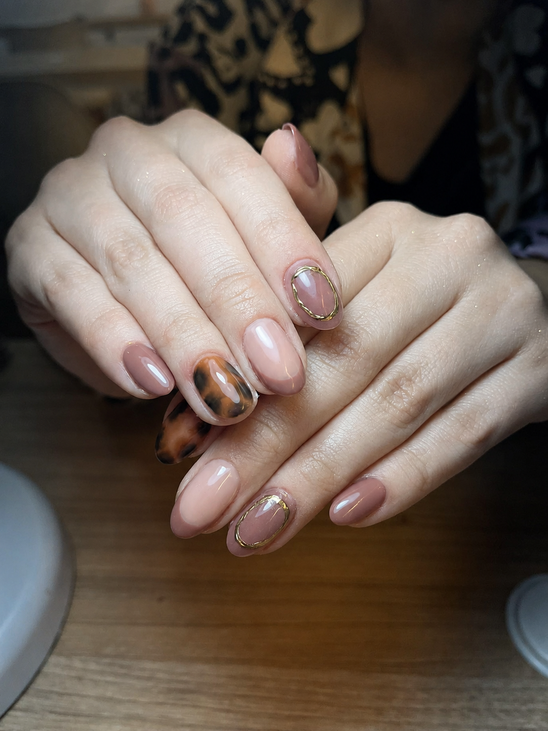 Manicure profesional con acabado cálido en Aura Nails Care — manos femeninas con diseño en tonos nude y marrón